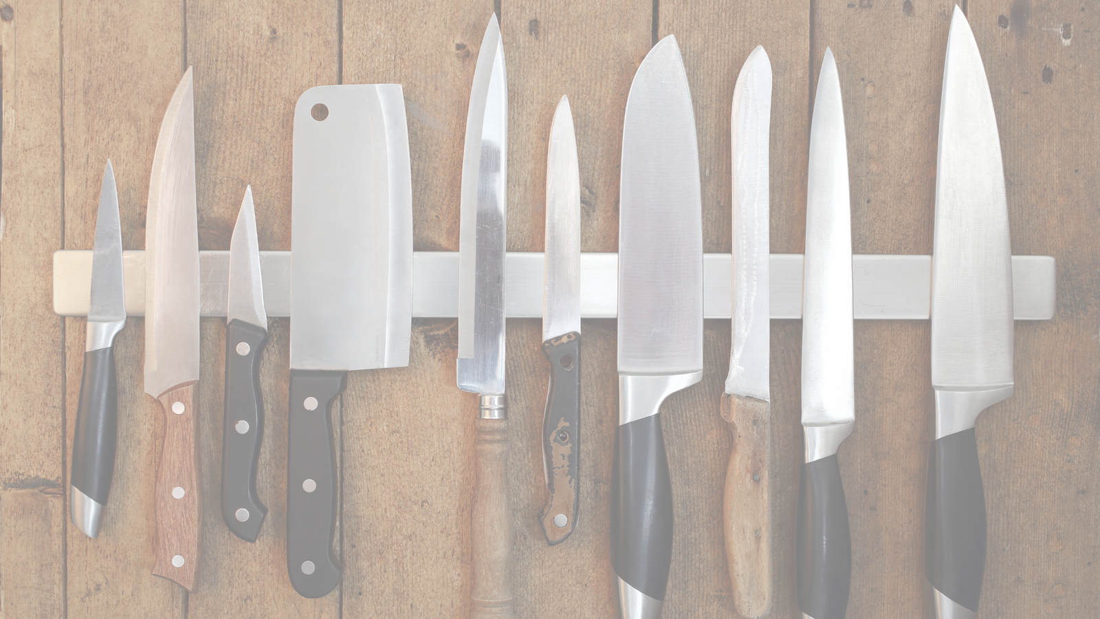 Selection of kitchen knives with different blade shapes and sharpening angles displayed on a magnetic knife rack.